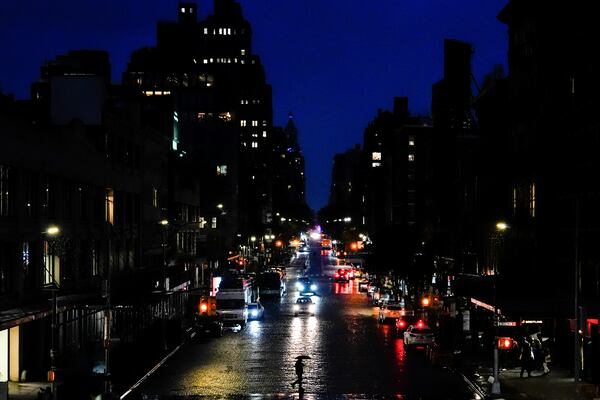 A person uses an umbrella while crossing a street in the Meatpacking District neighborhood of Manhattan, Friday, Nov. 22, 2024, in New York. (AP Photo/Julia Demaree Nikhinson)