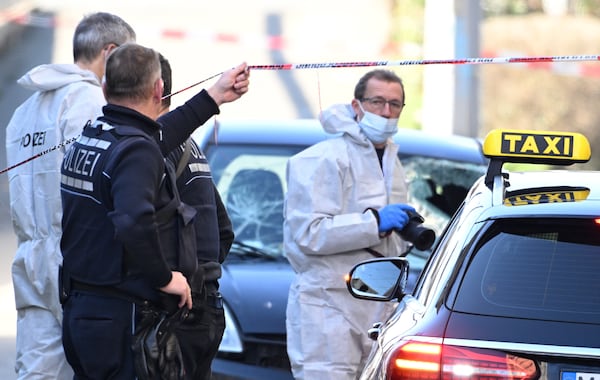 Forensics officers examine a damaged vehicle, background, at an access road to the Rhine bridge, in Mannheim, Germany, Monday March 3, 2025, following an incident in which one person was killed and others injured when a car rammed into a crowd, German police said. (Boris Roessler/dpa via AP)