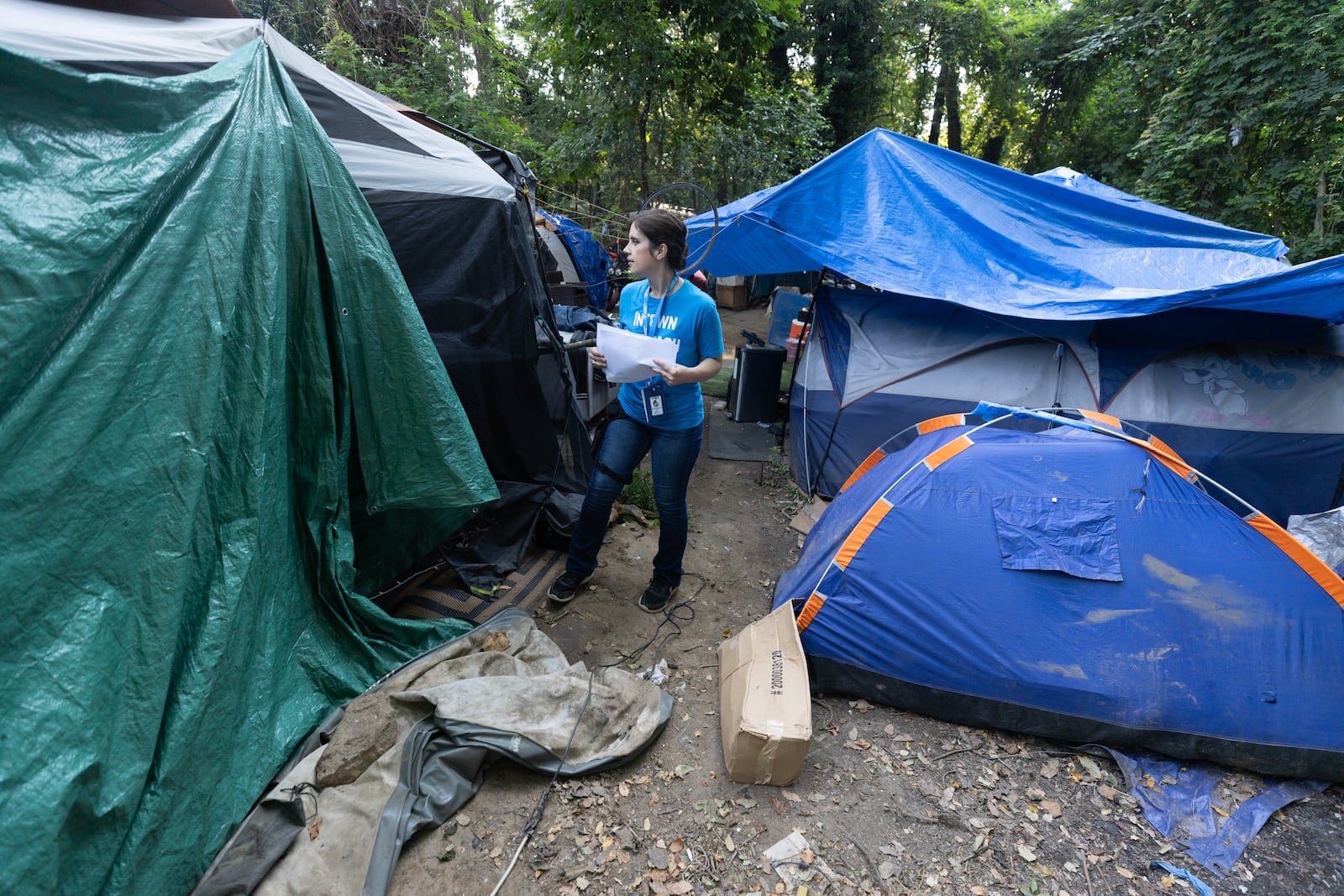 Intown Cares outreach representative Tracy Woodard checks on people and informs them of an upcoming free medical care opportunity at a homeless encampment Along the banks of the North Fork of Peachtree Creek near Buford Highway, Tuesday, August 22, 2023.  (Steve Schaefer/steve.schaefer@ajc.com)