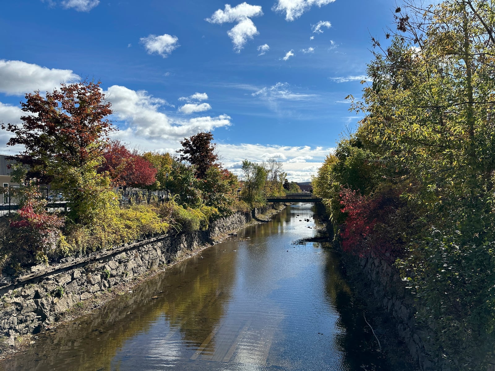 The leaves start to change by the canal under the Chestnut Street bridge in Lewiston, Maine, on Thursday, Oct. 15, 2024. (AP Photo/ Patrick Whittle)