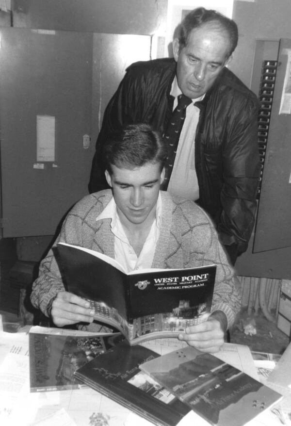 Morrow's Brian Ellis looks through a brochure from West Point with head coach Willie Oswalt in February 1989. (David Johnson / Staff)