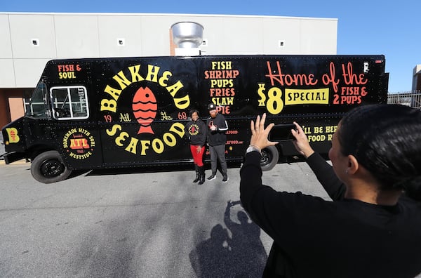 Chaka Dakers snaps a photo of Nichola Hines and Scott Fuller with the brand-new Bankhead Seafood food truck during a kickoff event for the business at Frederick Douglass High School on Thursday, Feb. 27, 2020, in Atlanta. The food truck is expected to hit Atlanta streets in late March or early April, while the restaurant’s reopening is planned for early 2021. CURTIS COMPTON / CCOMPTON@AJC.COM