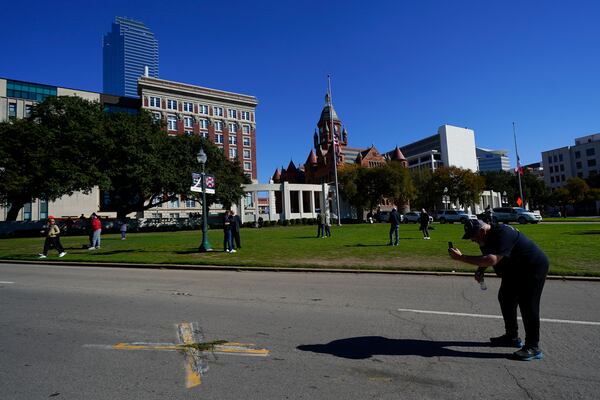 FILE - A person uses a cell phone to capture images of an X on Elm Street at Dealey Plaza, one of two spots marked where President John F. Kennedy was shot, as people gather on the 60th anniversary of his assassination, Nov. 22, 2023, in Dallas. (AP Photo/Julio Cortez, File)