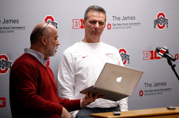 Ohio State coach Urban Meyer, right, receives word from sports information director Jerry Emig about the stipend that the playoff committee will give to players' families, during a news conference Tuesday, Jan. 6, 2015, in Columbus, Ohio. Ohio State faces Oregon in the national championship college football game on Jan. 12. (AP Photo/Columbus Dispatch, Adam Cairns) "Get a load of these ratings, coach Meyer." (Adam Cairns/Columbus Dispatch-AP photo)