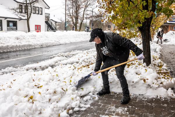 Salvador Garza shovels snow from the front of his shop Crystal Tones in Mt. Shasta, Calif.,, Thursday, Nov. 21, 2024, where runoff from rain and melting snow has begun to create standing water after an atmospheric river storm dumped significant precipitation in the area since Tuesday evening. (Carlos Avila Gonzalez/San Francisco Chronicle via AP)