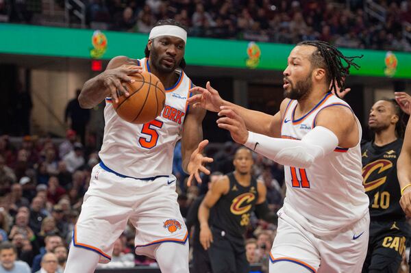 New York Knicks' Precious Achiuwa (5) grabs a rebound as teammate Jalen Brunson (11) looks on during the first half of an NBA basketball game against the Cleveland Cavaliers in Cleveland, Friday, Feb. 21, 2025. (AP Photo/Phil Long)