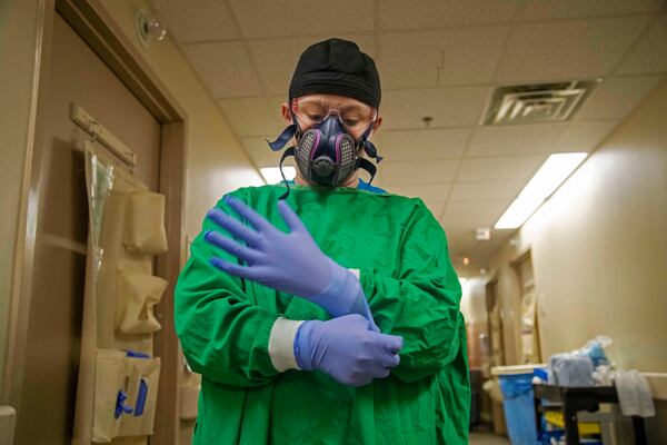 A nurse at Tanner Health System in Carrollton prepares to enter a patient's room on the COVID-19 isolation floor earlier this month.  Perhaps the severest factor in the overflow of hospitals is a nationwide shortage of nurses trained to deal with very ill patients.  (PHOTO by Alyssa Pointer / Alyssa.Pointer@ajc.com)