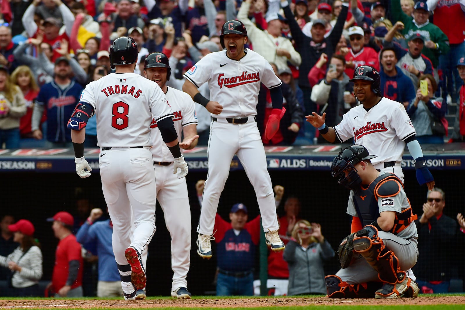 Cleveland Guardians players, from rear left, David Fry, Steven Kwan and Jose Ramirez greet teammate Lane Thomas after Thomas hit a grand slam in the fifth inning during Game 5 of baseball's American League Division Series against the Detroit Tigers, Saturday, Oct. 12, 2024, in Cleveland. Tigers catcher Jake Rogers is at right. (AP Photo/Phil Long)