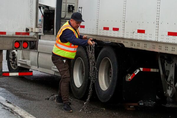 A trucker install snow chains to their tires during a storm Wednesday, Nov. 20, 2024, in Truckee, Calif. (AP Photo/Brooke Hess-Homeier)