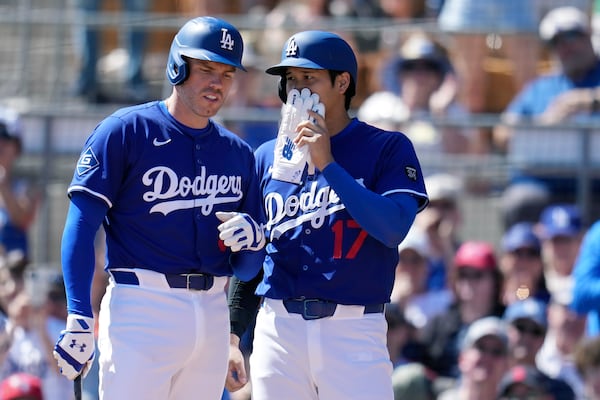 Los Angeles Dodgers' Shohei Ohtani (17), of Japan, talks with Freddie Freeman, left, during the first inning of a spring training baseball game against the Cleveland Guardians, Tuesday, March 11, 2025, in Phoenix. (AP Photo/Ross D. Franklin)