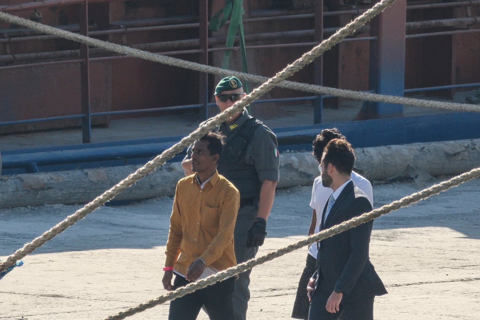 Migrants and security officials walk at the port of Shengjin, northwestern Albania. Wednesday, Oct. 16, 2024 after disembarking from the Italian navy ship Libra carrying the first group of 16 migrants intercepted in international waters. (AP Photo/Vlasov Sulaj)