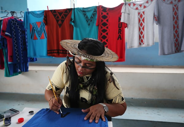 Jeicy Mura paints shirts with Indigenous themes during a gathering of the Mura Indigenous community in Autazes, Amazonas state, Brazil, Wednesday, Feb. 19, 2025. (AP Photo/Edmar Barros)