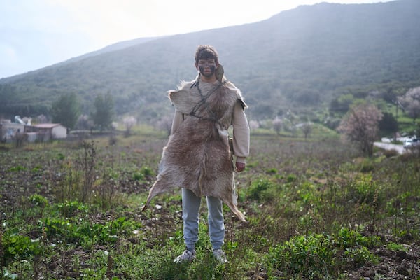 Mehmet Ahmetoglou, 17, poses for a portrait, dressed in animal skins and heavy bronze bells, as part of carnival celebrations in Distomo, a village in central Greece, on Monday, March 3, 2025. (AP Photo/Petros Giannakouris)