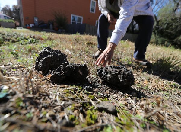 Rosario Hernandez rounds up chunks of slag, a byproduct of smelting, on the vacant lot next to her home near Mercedes-Benz Stadium on Nov. 25, 2019, in Atlanta. CURTIS COMPTON / CCOMPTON@AJC.COM