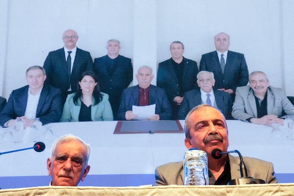 Pro-Kurdish Peoples' Equality and Democracy Party, or DEM, delegation members release an statement from the jailed leader of the rebel Kurdistan Workers' Party, or PKK, Abdullah Ocalan, center at the background photo, in Istanbul, Turkey, Thursday, Feb. 27, 2025. (AP Photo/Khalil Hamra)