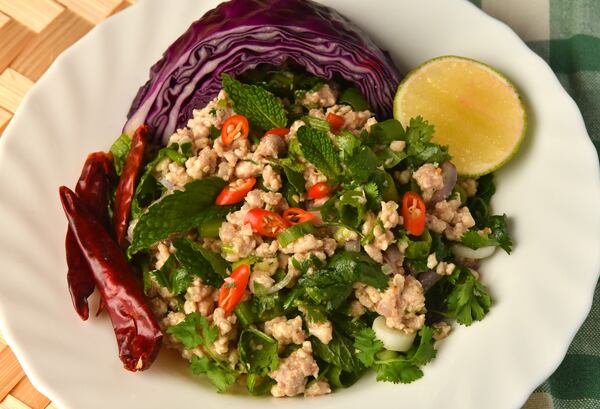 Laab Gai (Chicken Salad), made here by Ilene Rouamvongsor, is served with cabbage wedges and lime slices. (Styling by Ilene Rouamvongsor / Chris Hunt for the AJC) 