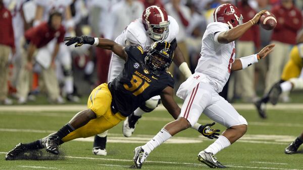 Alabama Crimson Tide quarterback Blake Sims scrambles to elude the tackle of Missouri Tigers defensive lineman Charles Harris during the 2014 SEC Championship at the Georgia Dome.