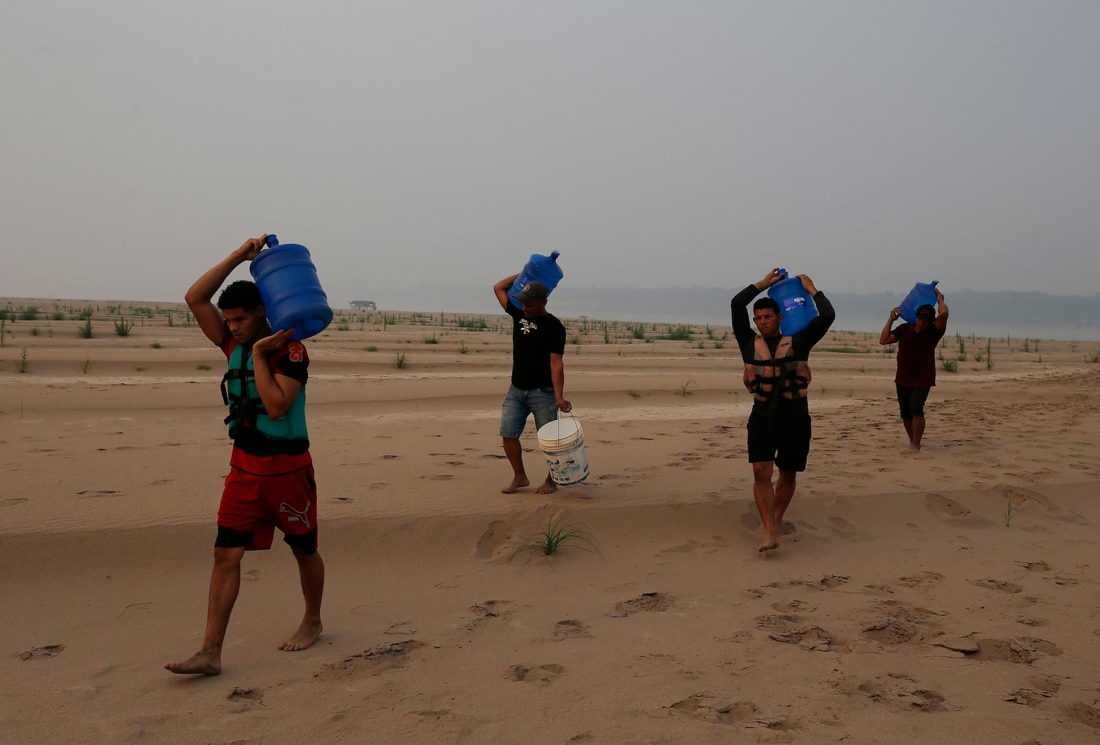 FILE - Residents transport drinking water from Humaita to the Paraizinho community, along a dry part of the Madeira River, a tributary of the Amazon River, amid a drought, Amazonas state, Brazil, Sep. 8, 2024. (AP Photo/Edmar Barros, File)