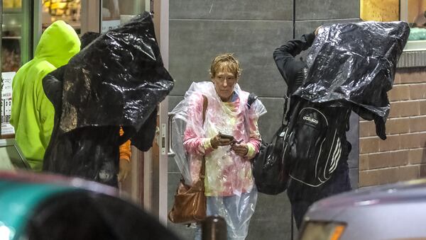 Becky Moore (center) tries to stay dry at the QuikTrip in the 3200 block of Buford Highway on Thursday morning as heavy rain moved across metro Atlanta.