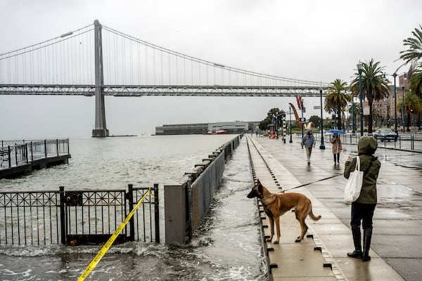 Water from the San Francisco Bay spills onto the Embarcadero in San Francisco on Saturday, Dec. 14, 2024, as a result of high tides and storm-driven waves. (AP Photo/Noah Berger)