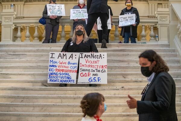 03/31/2021 —Atlanta, Georgia — Tamara Stevens, of No Safe Seats, holds protest signs on the South wing staircase during Sine Die, legislative day 40, at the Georgia State Capitol in Atlanta, Wednesday, March 31, 2021. (Alyssa Pointer / Alyssa.Pointer@ajc.com)