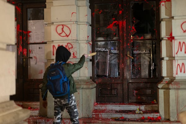 A protester points a baton at riot police inside the City Hall building in Novi Sad, Serbia, Tuesday, Nov. 5, 2024. (AP Photo/Marko Drobnjakovic)