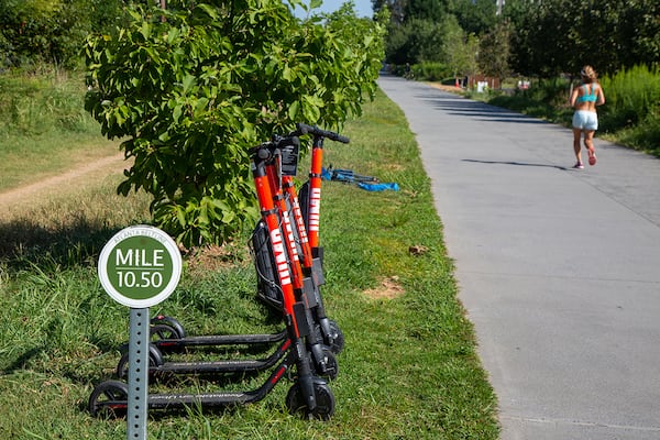 A runner passes a group of e-scooters on the Beltline near Ponce City Market in Atlanta on Thursday August 22nd, 2019. He shares his thoughts on e-scooters. The Beltline started out prohibiting motorized vehicles. In January, the Atlanta City Council passed a law allowing for e-scooters to be used on the trails. Does this compromise the Beltline's purpose?  (Photo by Phil Skinner)