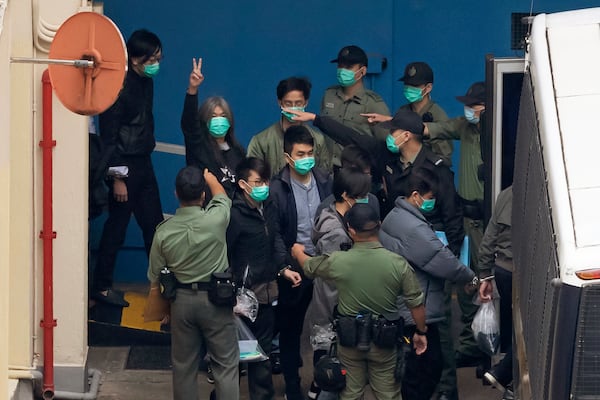 FILE - Former lawmaker Leung Kwok-hung, known as "Long Hair," second left, shows a victory sign as some of the 47 pro-democracy activists are escorted by Correctional Services officers to a prison van in Hong Kong, March 4, 2021. (AP Photo/Kin Cheung, File)