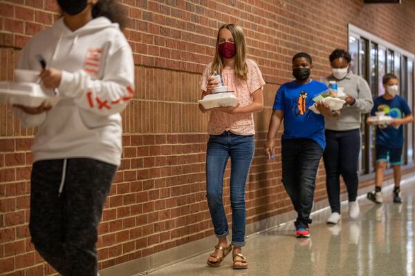 08/20/2020 - Cartersville, Georgia - Students walk at a social distance while carrying their lunches from the cafeteria to their classrooms at Cartersville Middle School in Cartersville, Thursday, August 20, 2020. They eat in their classrooms to minimize schoolwide mixing that could spread the coronavirus and to reduce the work involved in contact tracing should that become necessary. (ALYSSA POINTER / ALYSSA.POINTER@AJC.COM)