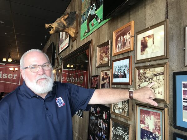 Longtime Manuel’s Tavern employee Bobby Agee points to photos of former bartenders from the storied Poncey-Highland watering hole, including recently deceased Bill McKloskey, who worked there for nearly 50 years. LIGAYA FIGUERAS / LFIGUERAS@AJC.COM