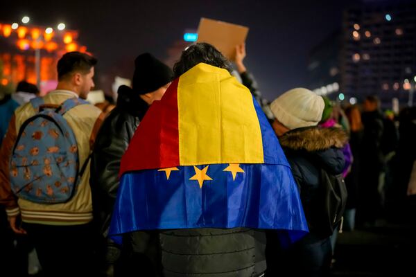 FILE - A man with the Romanian and European Union flags on his shoulders takes part in a protest against Calin Georgescu, the independent candidate for Romanian presidency who won the first round of elections, in Bucharest, Romania, Wednesday, Nov. 27, 2024.(AP Photo/Vadim Ghirda, File)