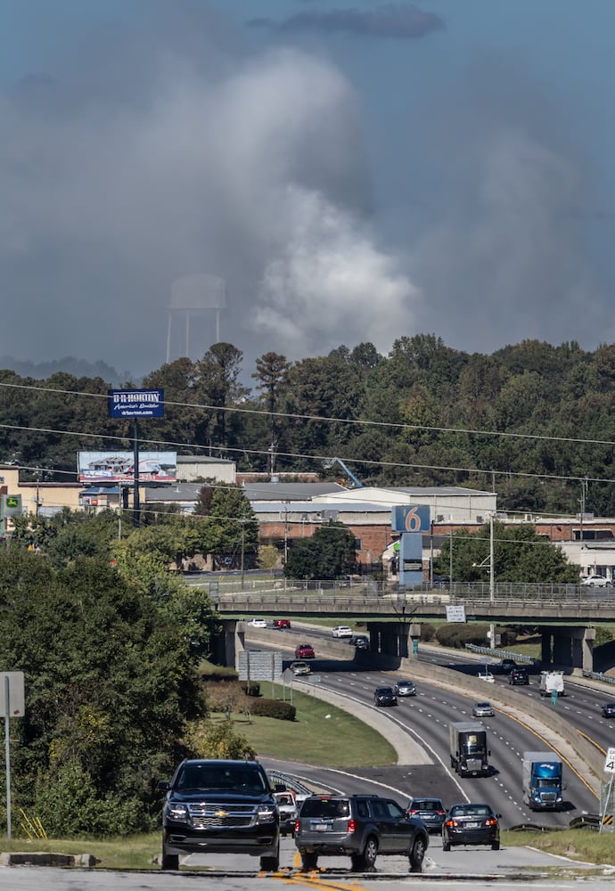 Traffic along iris Drive and I-20 move along at mid-morning Wednesday, Oct 2, 2024 as a large mile-long plume was still visible over Conyers as crews worked at the plant that caught on fire days earlier. But as the sun lifted above the horizon, so did the shelter-in-place order for Rockdale County residents. Those living nearby have been advised to stay inside every evening through early morning until Friday. (John Spink/AJC)