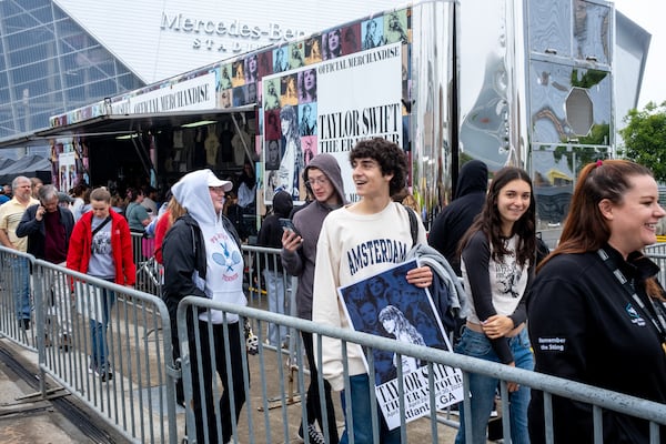 Luke McCullough of Atlanta holds a poster while waiting in line for Taylor Swift merchandise in front of Mercedes-Benz stadium in Atlanta on Thursday, April 27, 2023. (Arvin Temkar / arvin.temkar@ajc.com)