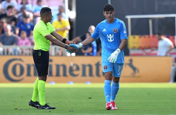 Inter Miami goalkeeper Oscar Ustari, right, shakes hands with an official as he walks off the field after being given a red card during the first half of an MLS soccer match against Charlotte FC, Sunday, March 9, 2025, in Fort Lauderdale, Fla. (AP Photo/Lynne Sladky)