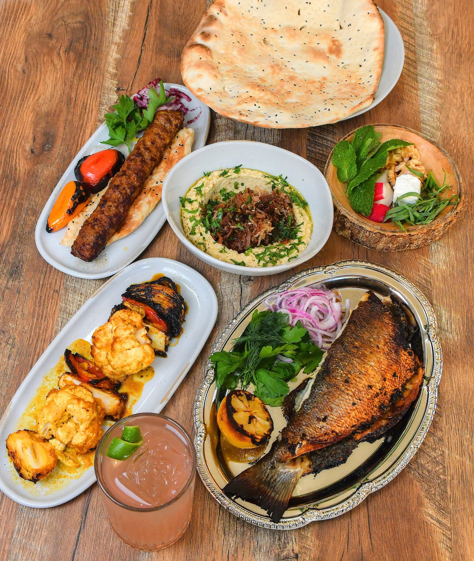 Delbar offers Persian delights, including, clockwise from top: herb cheese and bread, stuffed trout, hummus with lamb and za'taar (center), koobideh and grilled veggies. Chris Hunt for The Atlanta Journal-Constitution