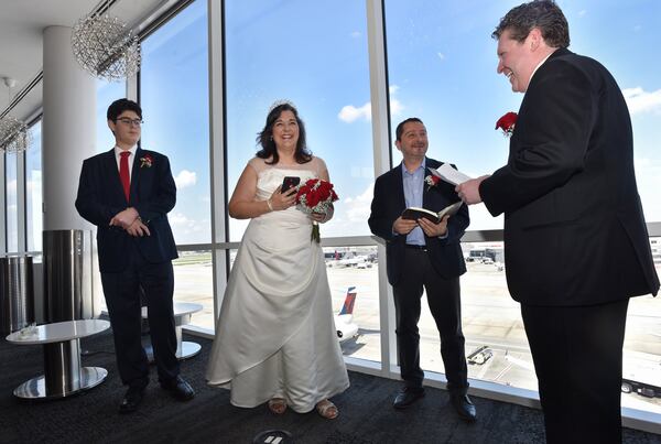 July 2, 2019 Atlanta - Sarah Lora (second from left) and Cody Kaufman (right) exchange wedding vows as Gabriel Bugarin (third from left) officiates during their wedding at Delta Sky Club in Hartsfield-Jackson Atlanta International Airport on Tuesday, July 2, 2019. (Hyosub Shin / Hyosub.Shin@ajc.com)