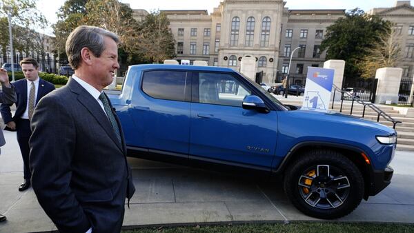 FILE - In Atlanta, Republican Gov. Brian Kemp stands next to a Rivian electric truck while announcing the company's plans to build a plant east of Atlanta, Dec. 16, 2021. (Courtesy of John Bazemore/AP)