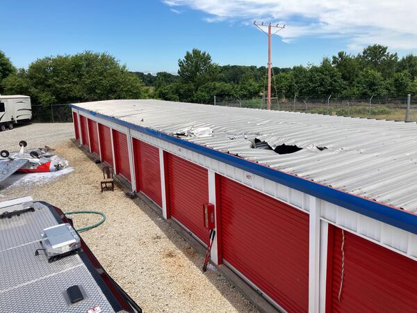 The small plane damage the roof of the storage facility before landing upside down on the ground below.