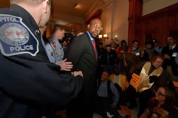 The Rev Raphael Warnock is arrested in front of the governor's office at the Georgia Capitol during a rally in 2014. Since becoming the pastor of Atlanta's Ebenezer Baptist Church, Warnock has led voter registration drives, advocated for the expansion of Medicaid, hosted a climate change summit with Al Gore, opposed capital punishment and pushed for an overhaul of criminal justice policy. KENT D. JOHNSON / KDJOHNSON@AJC.COM