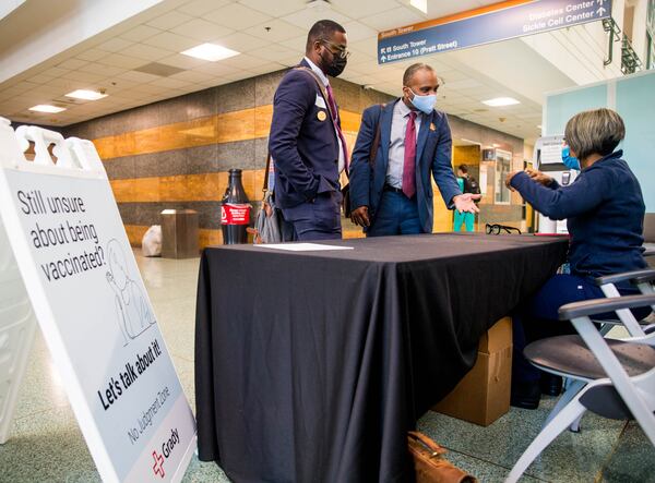 In this file photo, Grady Hospital staffs a vaccine question desk in the main lobby of the hospital with Emory professor Dr Kimberly Manning, seated on right, who is available in the 'no judgement zone' for anyone with concerns or questions still looking for information on the Covid vaccinations.  Charquavis Bell, left, is with his co-worker, Mark Holland, center, who received the J&J vaccine and has a question about booster shots.   (Jenni Girtman for The Atlanta Journal-Constitution)