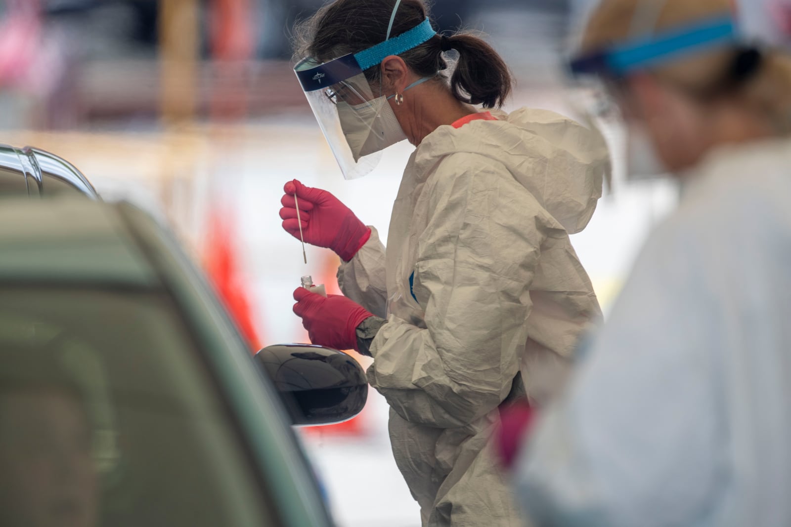 05/14/2020 - Gainesville, Georgia  - A medical healthcare worker drops a specimen collection into a container after testing a motorist for COVID-19 at a community testing site in the parking lot of La Flor de Jalisco #2 during a visit to Gainesville, Friday, May 15, 2020.  (ALYSSA POINTER / ALYSSA.POINTER@AJC.COM)