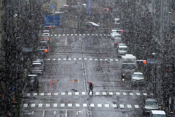 A woman walks in falling snow Saturday in Tokyo. Tokyo Gov. Yuriko Koike has repeatedly asked the city’s 13 million residents to stay home this weekend, saying the capital is on the brink of an explosion in virus infections.