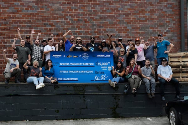 Workers from Monday Night Brewery pose with rapper Killer Mike (center) and members of the nonprofit PAWKids, who received a $15,000 donation. In addition, The Eastern, NZ Hops and Yakima Chief Hops contributed financially to help the nonprofit with its community outreach programs. (Photo: Miguel Martinez / miguel.martinezjimenez@ajc.com)