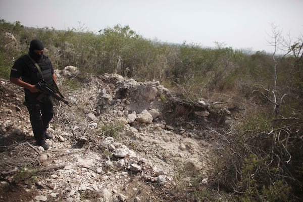 FILE - An officer walks past a hole that police say was used as a mass grave, near San Fernando, Tamaulipas state, Mexico, April 27, 2011. (AP Photo/Alexandre Meneghini, File)