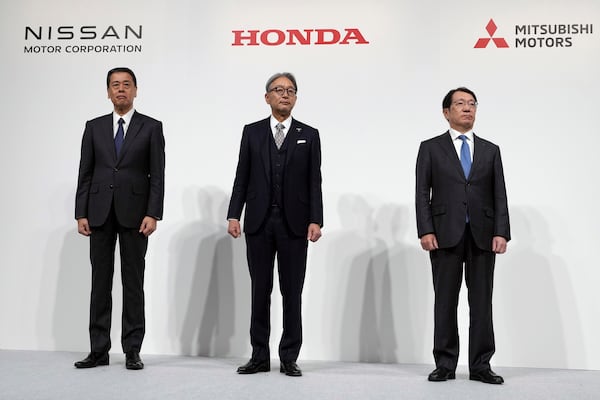 Nissan Chief Executive Makoto Uchida, left, Honda Chief Executive Toshihiro Mibe, center, and Takao Kato, CEO of Mitsubishi Motors, right, pose for photographers during a joint news conference in Tokyo, Japan, Monday, Dec. 23, 2024. (AP Photo/Eugene Hoshiko)