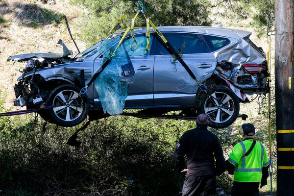 FILE - Workers watch as a crane is used to lift a vehicle following a rollover accident involving golfer Tiger Woods, Feb. 23, 2021, in the Rancho Palos Verdes section of Los Angeles. (AP Photo/Ringo H.W. Chiu, file)