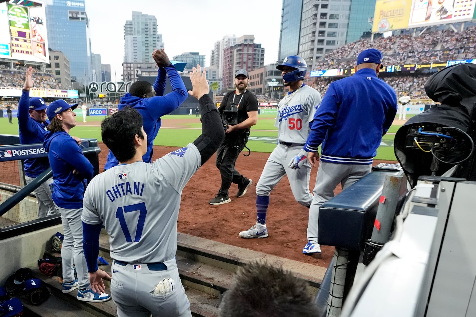 Los Angeles Dodgers' Mookie Betts (50) celebrates his solo home run with teammates in the dugout during the first inning in Game 4 of a baseball NL Division Series against the San Diego Padres, Wednesday, Oct. 9, 2024, in San Diego. (AP Photo/Ashley Landis)