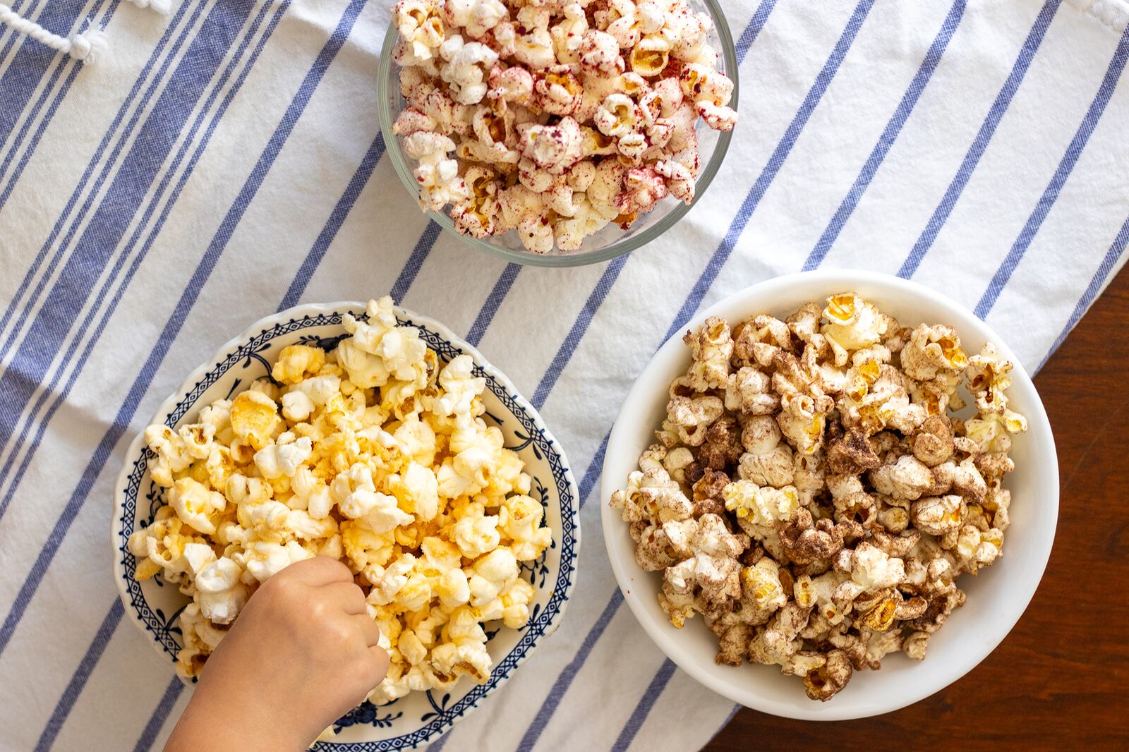 Kids of all ages can enjoy a variety of flavored popcorn, such as (from top, clockwise) freeze-dried fruit-flavored popcorn, hot cocoa mix-flavored popcorn and cheese-flavored popcorn. (Kate Williams for The Atlanta Journal-Constitution)