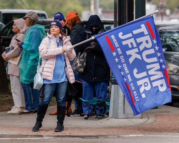 A woman waves a Donald Trump and John F. Kennedy Jr. flag along Elm Street at Dealey Plaza Tuesday in downtown Dallas. The group believes John F. Kennedy Jr., who died in plane crash in 1999, will return and reinstate Donald Trump as president. 