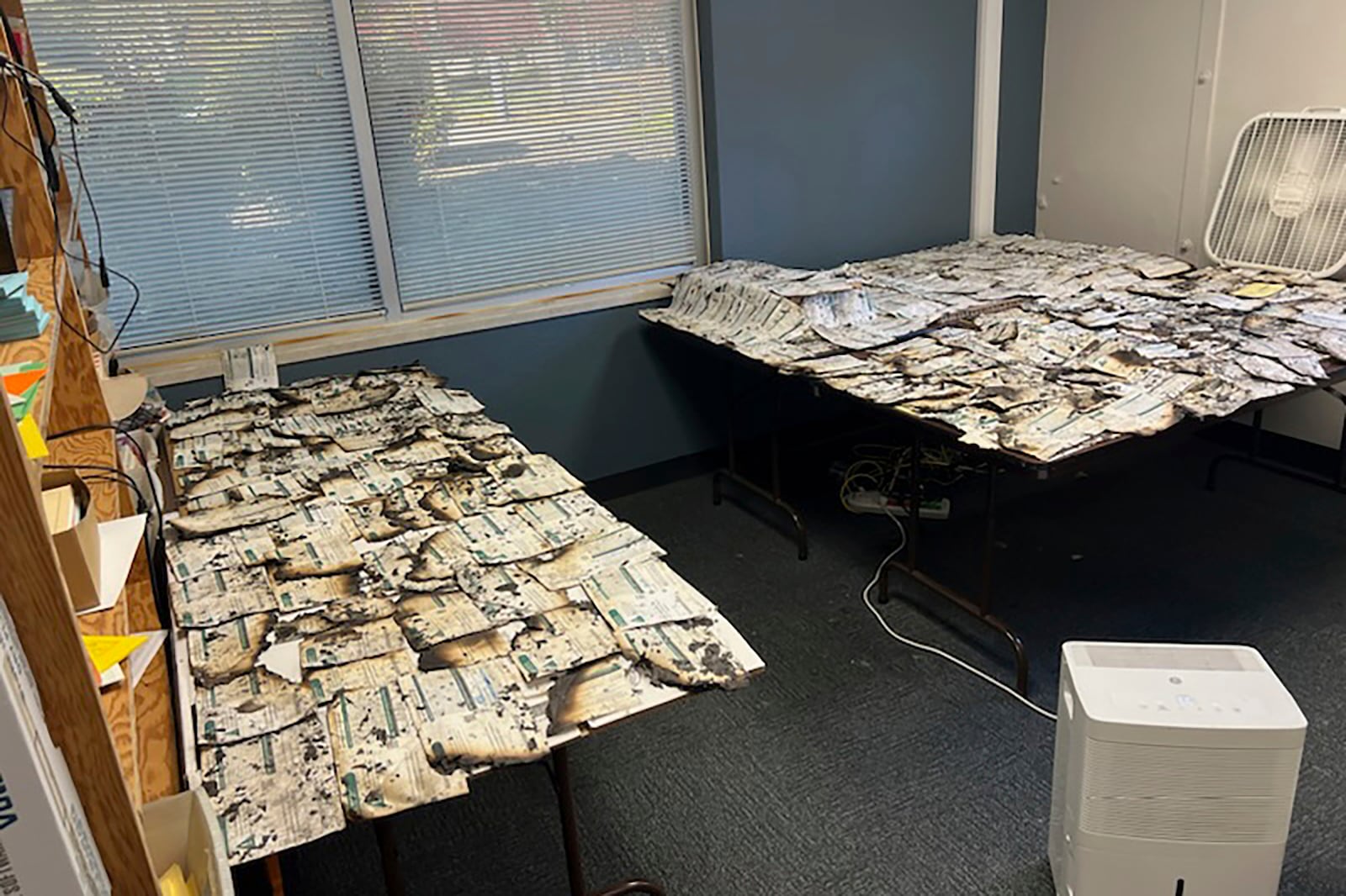 In this image provided by the Clark County Auditor's Office, ballots damaged in a drop box arson in Vancouver, Wash., are spread on tables on Monday, Oct. 28, 2024. (Greg Kimsey/Clark County Auditor's Office via AP)